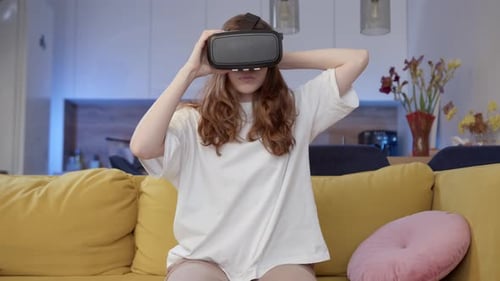 Woman Using VR Headset on Yellow Couch Indoors
