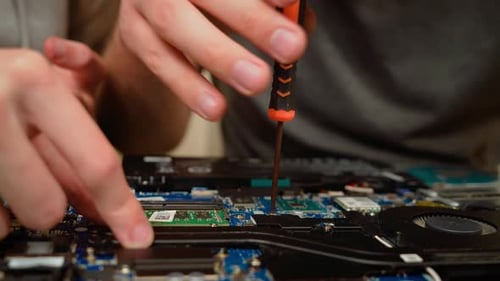 Man Repairing Computer Hardware with Screwdriver