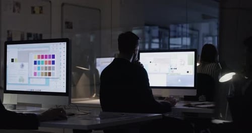 People Working at Computers in Modern Office at Night