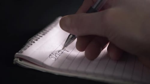 Escritura a mano de la lista de compras en el bloc de notas, primer plano