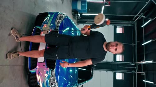 Man Polishing Car with Power Buffer in Garage
