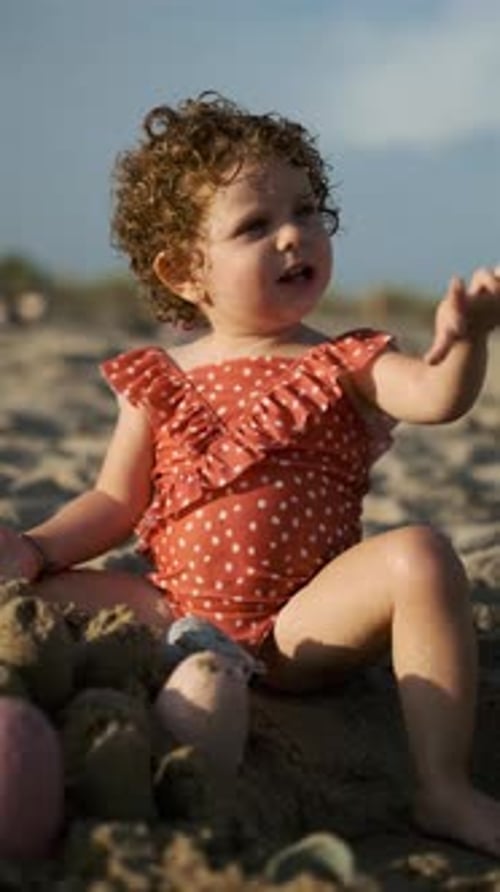 Toddler Playing with Sand at the Beach in a Summer Day at Sunset