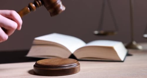 Judge with gavel at wooden table in office, closeup