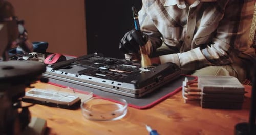 Ein Teenager reinigt einen zerlegten Laptop von Staub, repariert und wartet Geräte und