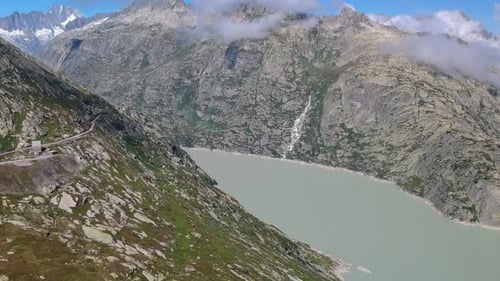 Panning drone shot over Grimselsee in Switzerland, looking out over the mint coloured water to the s