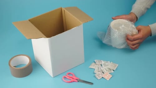 Mujer latina empacando un pedido dentro de una caja de cartón blanca, comercio electrónico, entrega de paquetes