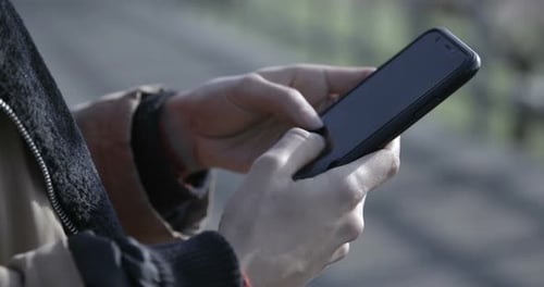 Close Up of a woman browsing and texting on her phone outdoors