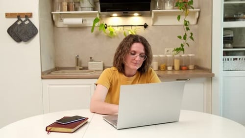Woman Working on Laptop in Bright Kitchen