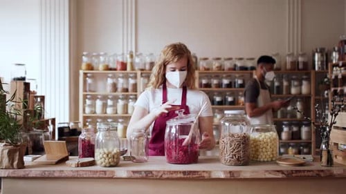 Young Woman Filling Jar by Dryed Raspberries in Zero Waste Shop. Coronavirus
