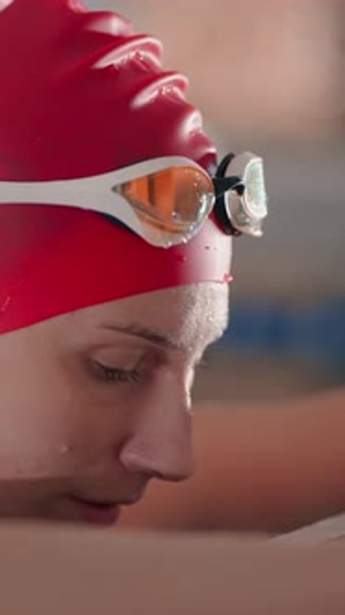 Focused Competitive Swimmer in Red Cap Preparing at Pool Edge Water Droplets on Face Intense Gaze