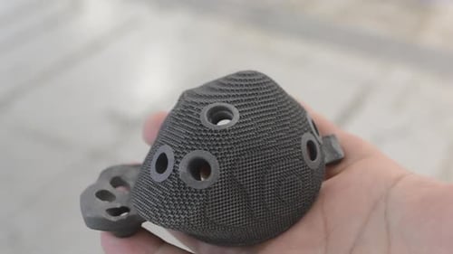 Imprimante 3D imprimée par une personne tenant un implant de la main en titane biocompatible