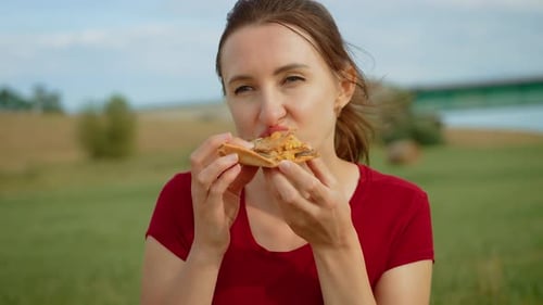 Cheerful Woman Eating Pizza in Rural Area Smiling Female Enjoying Slice of Pizza Outdoors in