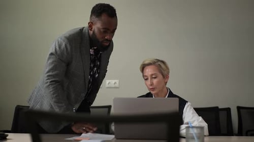 Man and Woman Discussing Work on Laptop Indoors