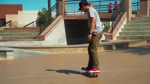 Slow Motion shot of young male Skateboarder Riding Skateboard at Skate Park performing a trick