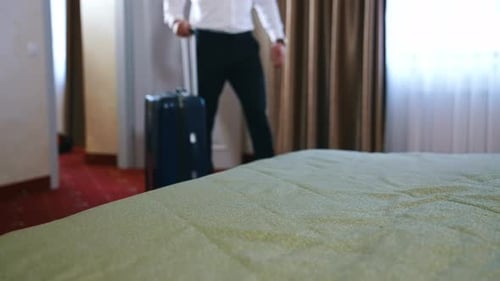 Unrecognizible businessman has just entered a hotel room and ready to unpack suitcase.