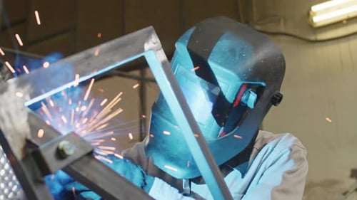 Man Welding Metal Construction in Workshop