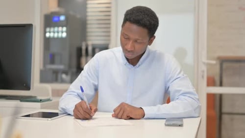 African Businessman Working on Documents in Office
