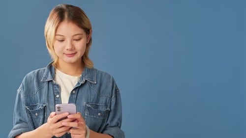 Young woman using mobile phone isolated on blue background