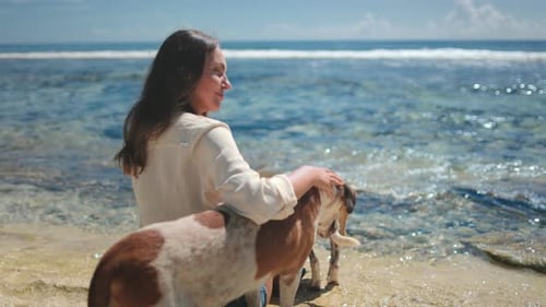 Young Woman Petting Dogs and Relaxing on the Beach