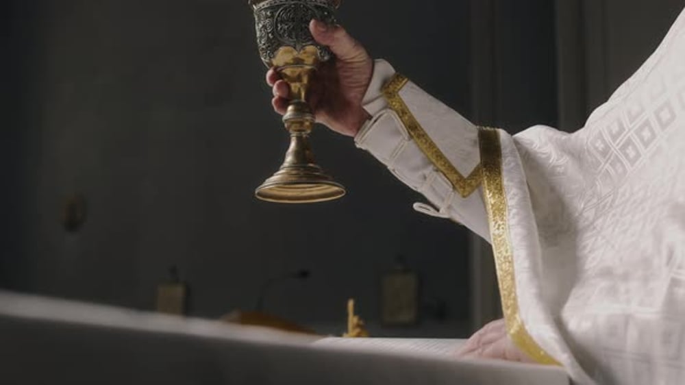 Hand of Priest Raising Chalice Cup in Church