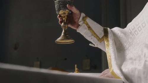 Hand eines Priesters, der Kelchbecher in der Kirche erhebt