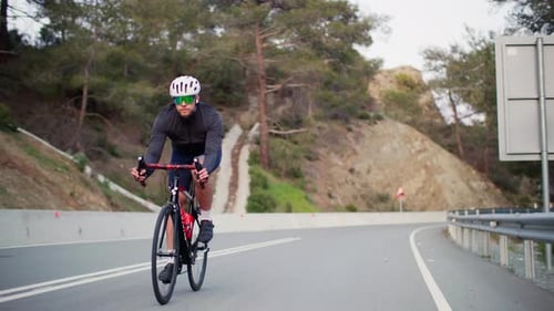Ein Mann fährt Fahrrad auf einer Autobahn in einer Berglandschaft