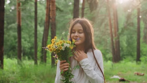 Portrait Of Girl Holding Wildflower Bouquet And Smiling In Green Forest