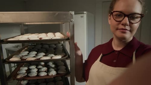 Baker Stands Next to a Rack of Cookies