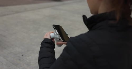 Woman Holding Smartphone on Handheld Gimbal Stabilizer