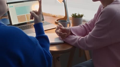 Adults Discussing Work at Desk with Laptop
