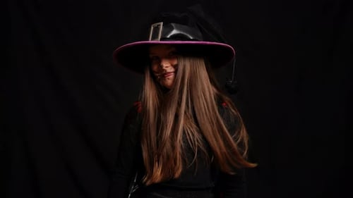 Girl in Witch Costume Posing Against Dark Background