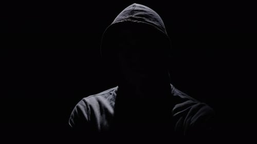 Mystical Person in a Hood in a Dark Room