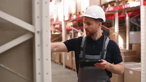 Checking the products. Storage worker in uniform is in the warehouse