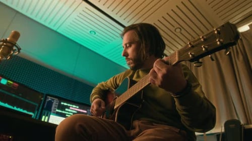 Artist Playing Song on Guitar and Recording Sound on Computer in Studio