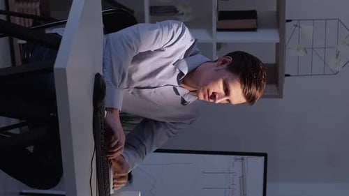 Young Man Typing at Desk in Office at Night