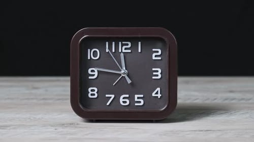 The Pointer Clock on Wooden Table and Black Background Show Time