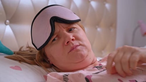 Woman sleeps in bed, wakes up, finger gesture asks for silence not to make noise