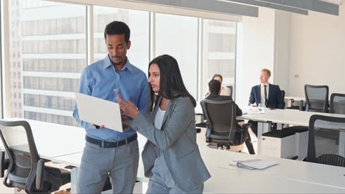 Des employés de divers horizons utilisent un ordinateur portable pour discuter d'un projet d'entreprise travaillant au bureau