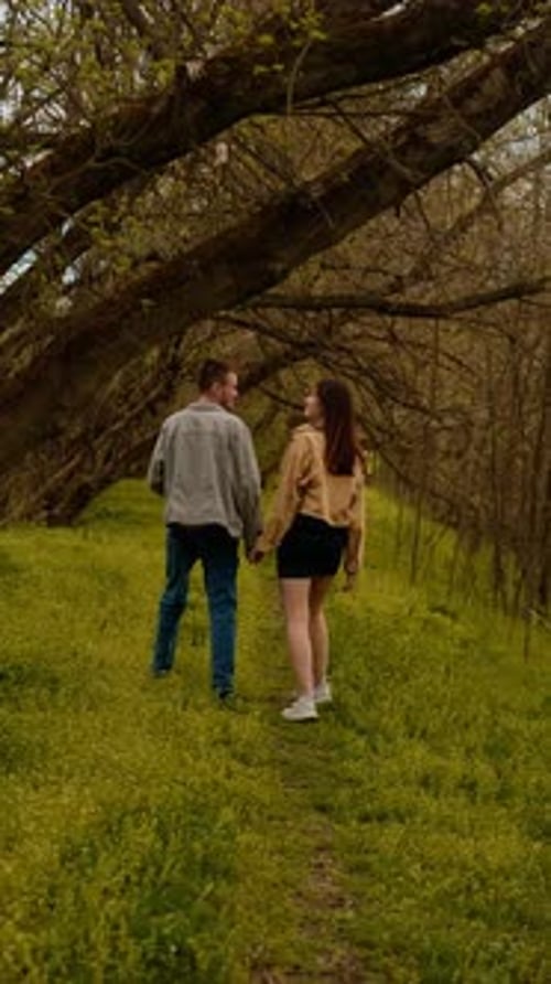 A young couple holding hands run through the forest, embodying an active lifestyle and tourism. Spor