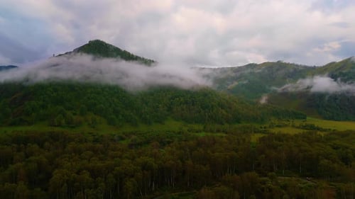 Drone flight over mountains in fog early in the morning in the Altai Mountains.