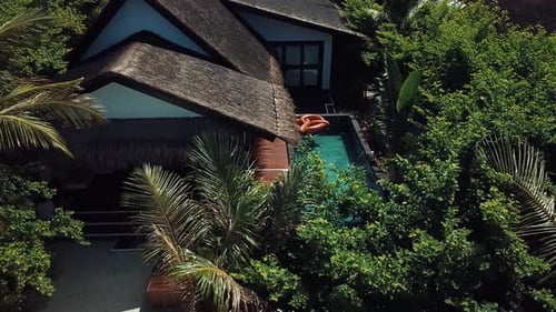 Vídeo de drone de uma vila tropical nas Maldivas, palmeiras verdes, clima ensolarado, piscina de água turquesa, i