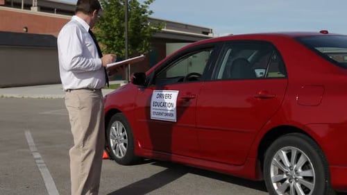 Driving instructor taking notes during a teenager driving lesson