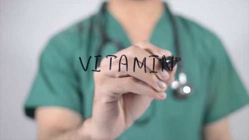 Doctor Writes Vitamins on Glass Close Up