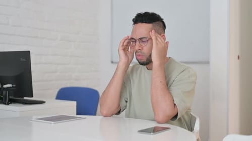Stressed Man Rubbing Temples at Office Desk