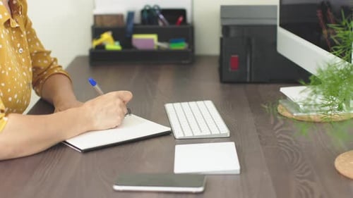 Person Writing at Desk in Workplace or Home