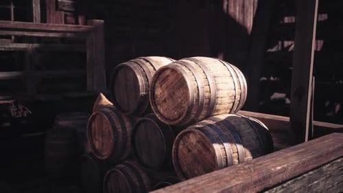 Stacked Wooden Barrels in a Rustic Storage Area During Daylight Hours
