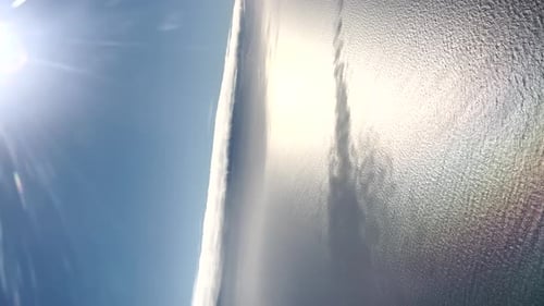 Vertical aerial view of the blue sky and sea on a clear day, with bright sunshine and gentle water r