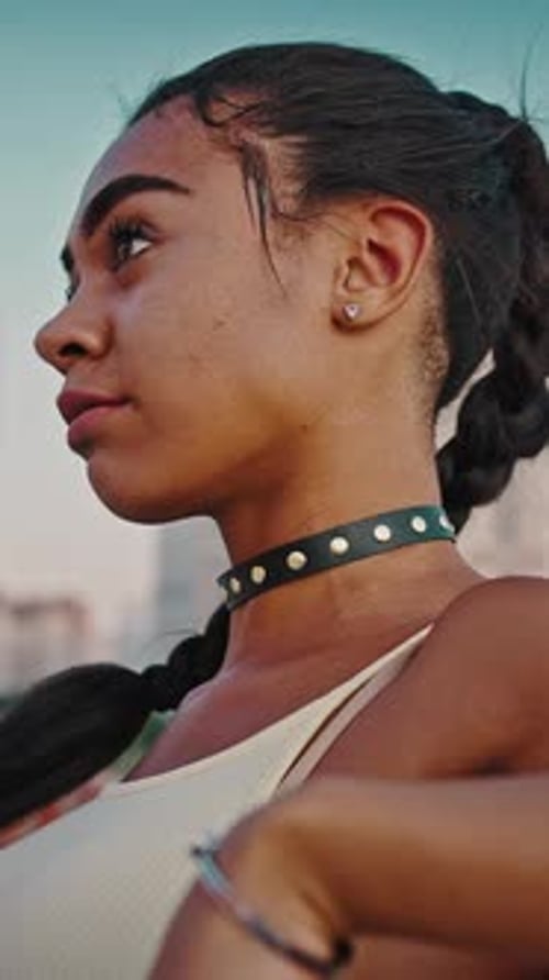 Joven y moderna mujer afroamericana relajándose al aire libre de pie sola en un distrito residencial
