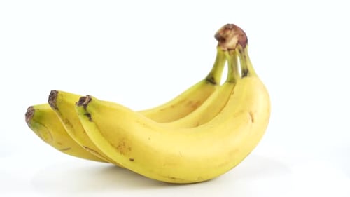 Close-up video of ripe yellow bananas spinning on a white background.