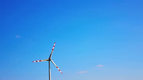 Wind turbine with red lines rotate in the blue sky. Generating green energy. Low angle view.
